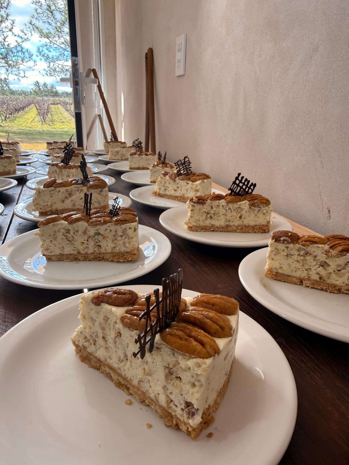 Porciones de torta de nuez con decoración de chocolate servidas en platos blancos, junto a un ventanal